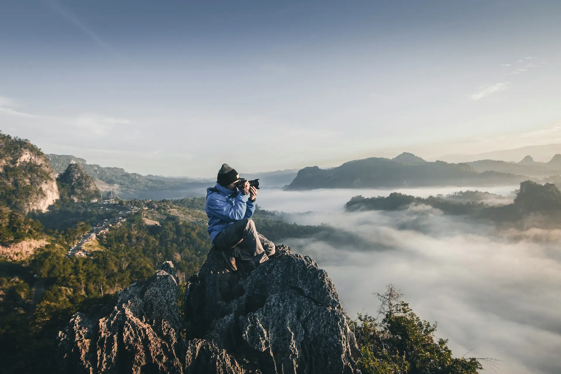 Fotógrafo capturando un paisaje montañoso envuelto en nubes, simbolizando la creatividad en cada detalle y la inspiración en la naturaleza.