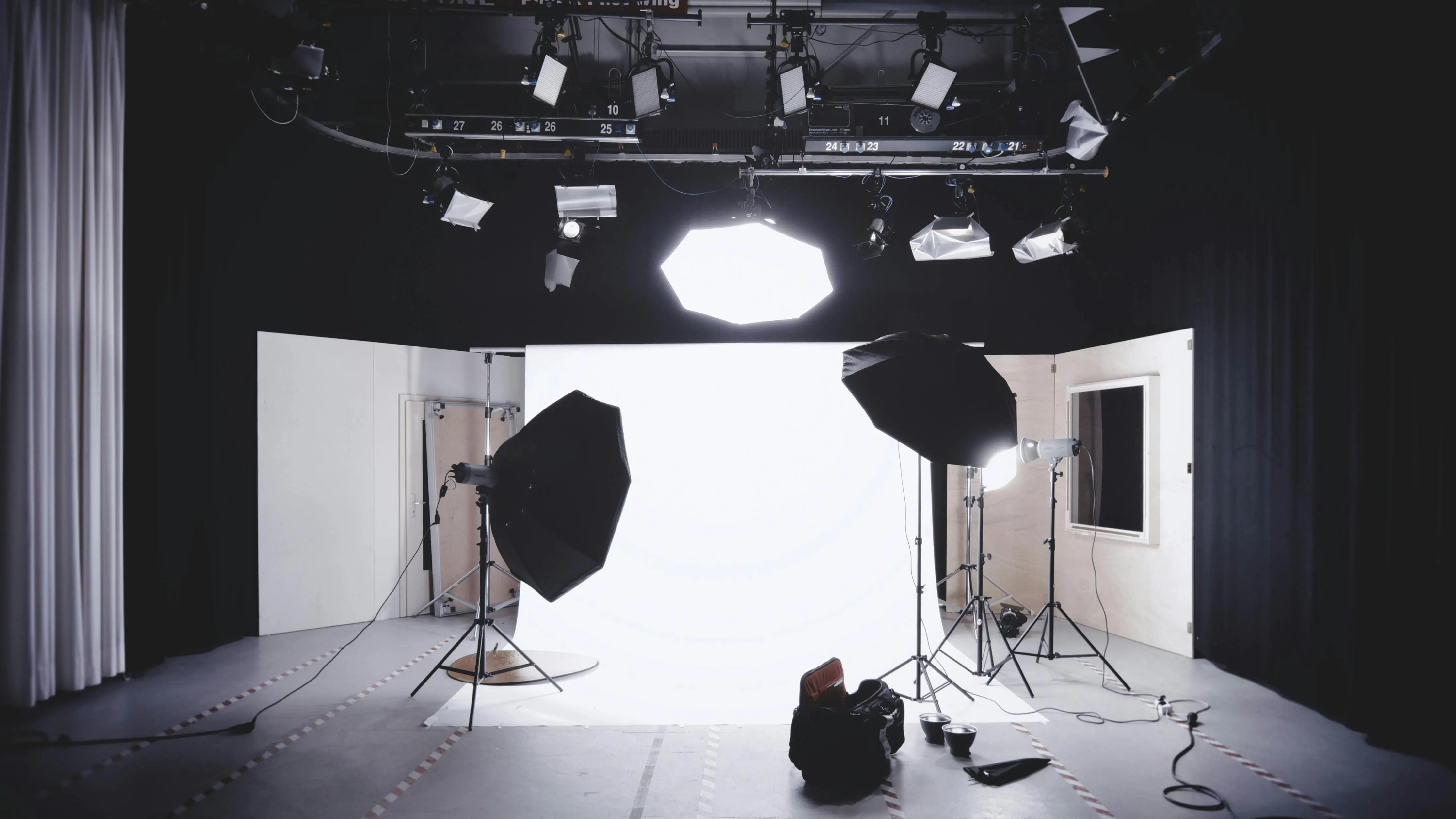 Estudio de fotografía profesional con fondo blanco, iluminación de estudio, softboxes y equipo fotográfico listo para una sesión.